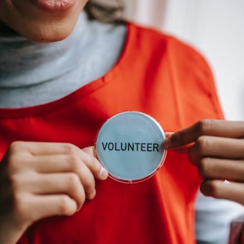 Person wearing orange shirt with a 'volunteer' pin
