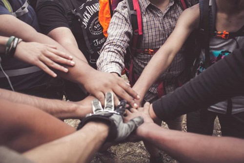 Image of group of people putting their hands together in the center