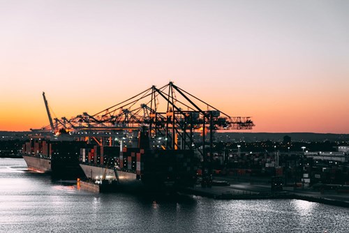 Port along a body of water with large cranes during sunset. 