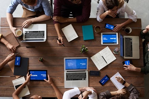 People sitting around a large table on their computers.