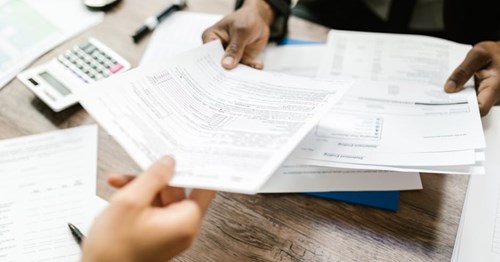 Person handing over a document to another person. 