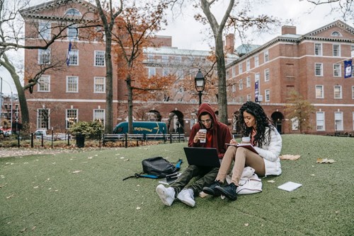 Students sitting in front of university/college building