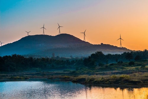 Wind turbines on top of a large hill during sunset